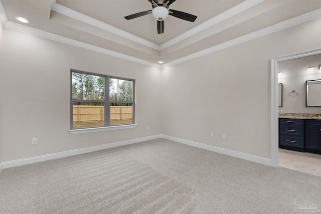 unfurnished bedroom featuring crown molding, ceiling fan, connected bathroom, a tray ceiling, and light colored carpet