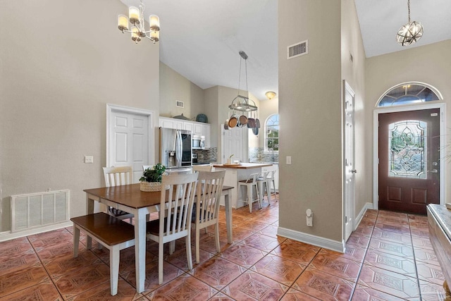 dining room featuring tile patterned floors, high vaulted ceiling, plenty of natural light, and a notable chandelier