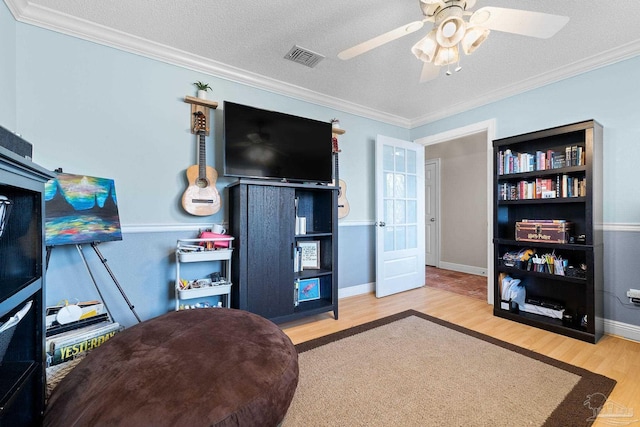 interior space with ceiling fan, hardwood / wood-style floors, a textured ceiling, and ornamental molding