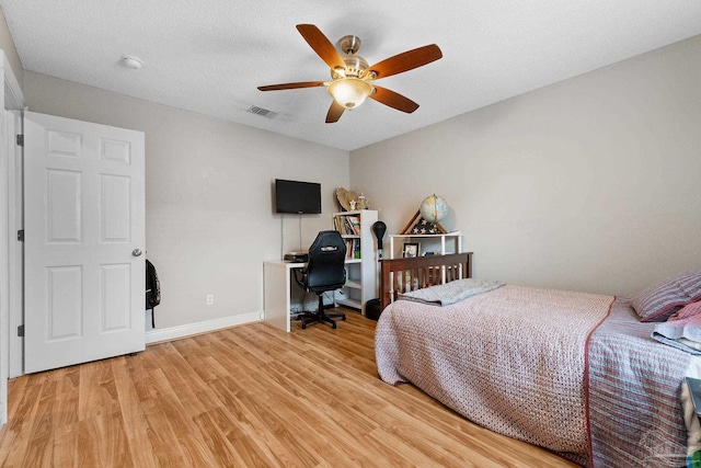 bedroom with a textured ceiling, light hardwood / wood-style flooring, and ceiling fan