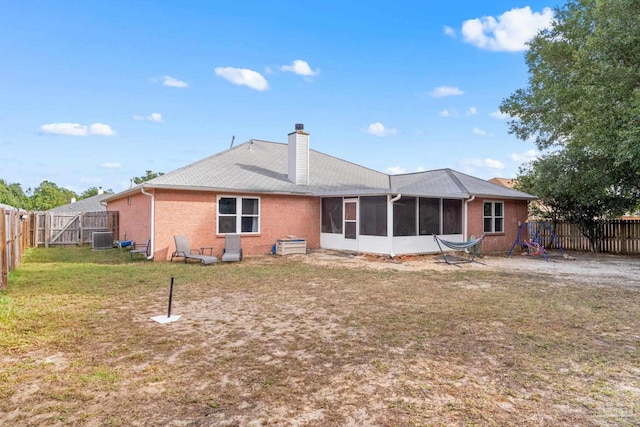 rear view of property featuring a lawn, cooling unit, and a sunroom