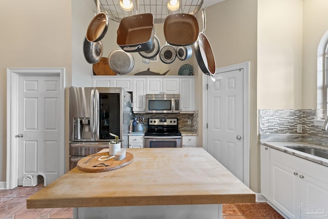 kitchen with decorative backsplash, white cabinetry, sink, and appliances with stainless steel finishes