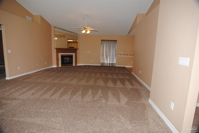 unfurnished living room with ceiling fan, lofted ceiling, carpet floors, and a tiled fireplace