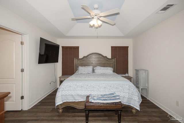 bedroom featuring dark hardwood / wood-style floors, ceiling fan, and a tray ceiling