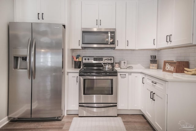 kitchen featuring white cabinetry, tasteful backsplash, stainless steel appliances, and wood-type flooring