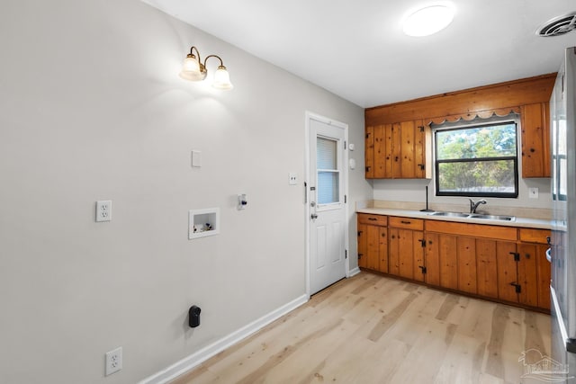 laundry area featuring cabinets, hookup for a washing machine, light hardwood / wood-style flooring, and sink