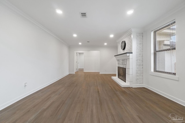 unfurnished living room with a large fireplace, ornamental molding, and dark wood-type flooring