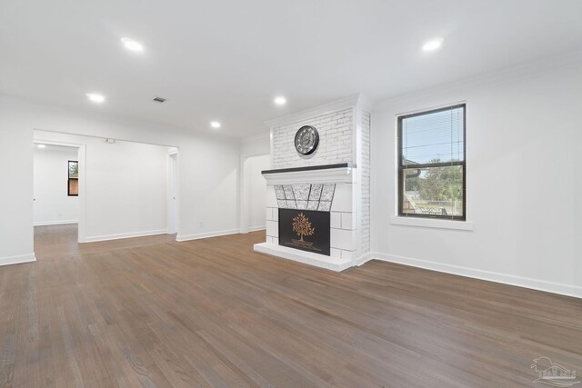 unfurnished living room featuring crown molding, dark hardwood / wood-style flooring, and a brick fireplace