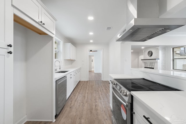 kitchen featuring white cabinetry, sink, stainless steel appliances, and wall chimney range hood