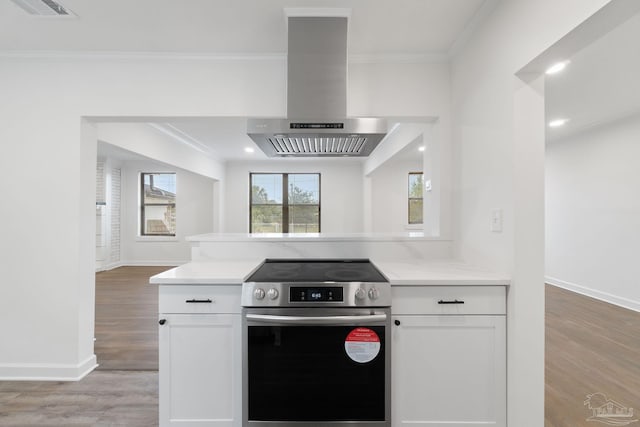 kitchen with visible vents, stainless steel range with electric cooktop, exhaust hood, crown molding, and light countertops