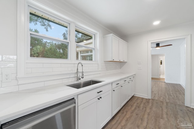 kitchen with white cabinets, sink, stainless steel dishwasher, light wood-type flooring, and tasteful backsplash