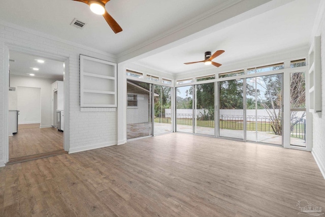 unfurnished living room featuring floor to ceiling windows, ornamental molding, brick wall, ceiling fan, and wood-type flooring