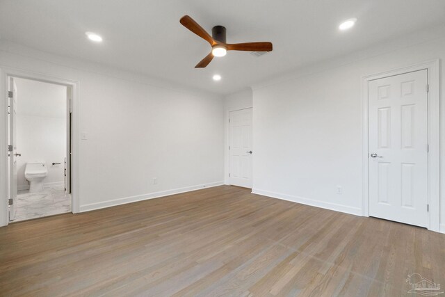 unfurnished bedroom featuring ceiling fan, baseboards, recessed lighting, wood finished floors, and ensuite bath