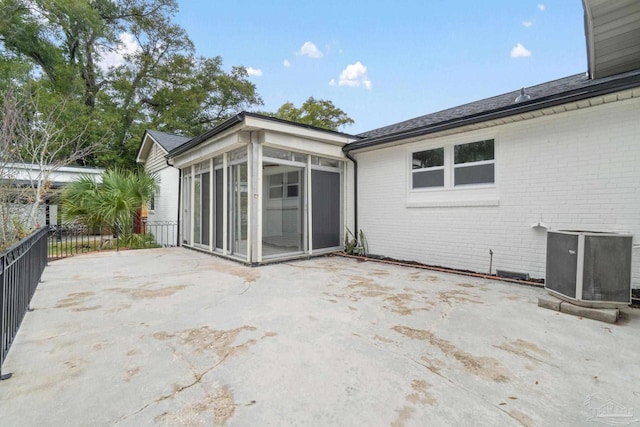 back of house with cooling unit, a patio, brick siding, and a sunroom