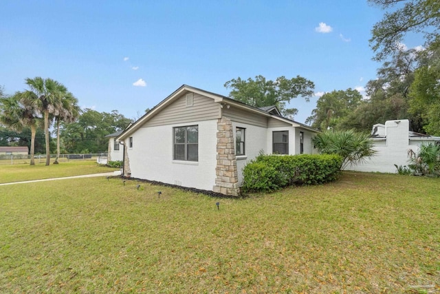 view of property exterior with a yard, brick siding, and fence