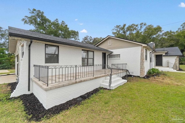 rear view of property featuring a yard and brick siding