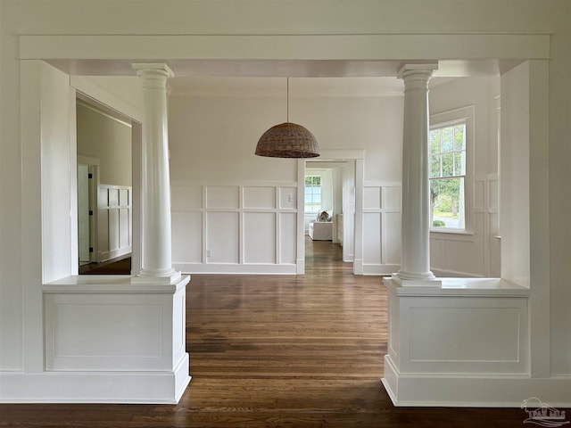 corridor featuring dark wood-type flooring and ornate columns