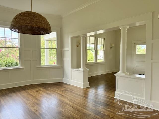 empty room featuring decorative columns, ornamental molding, and dark hardwood / wood-style floors