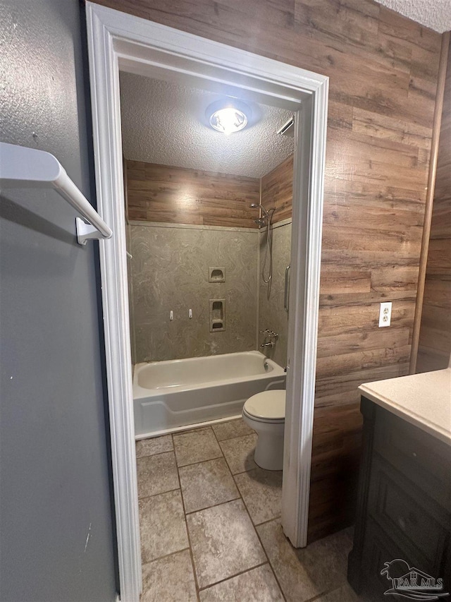 full bath with toilet, a textured ceiling, wood walls, washtub / shower combination, and vanity