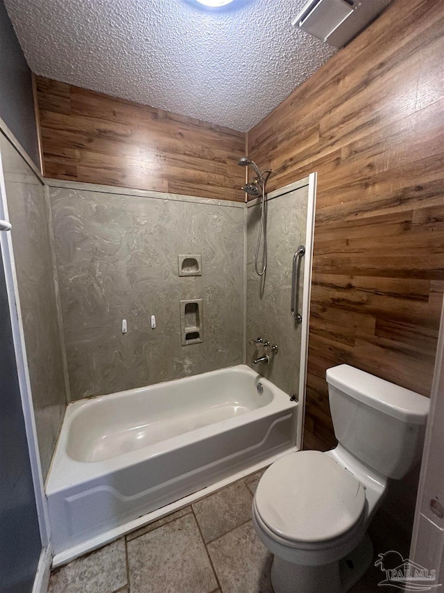full bath featuring toilet, wooden walls, and a textured ceiling