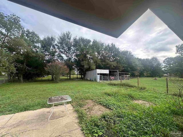 view of yard featuring an outdoor structure, a pole building, and fence