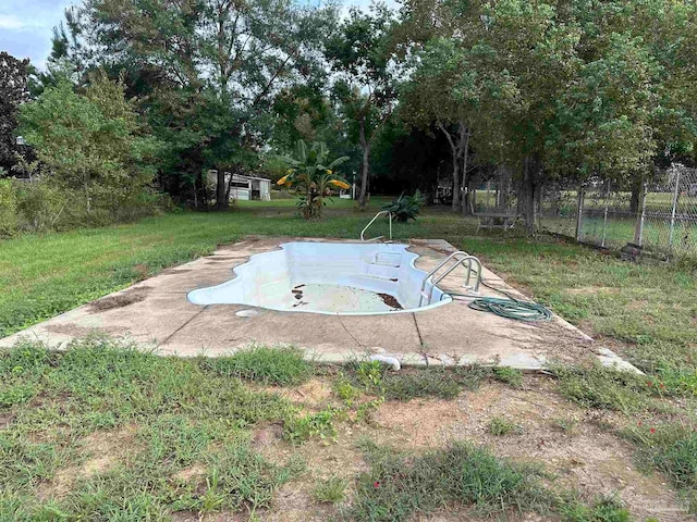 view of swimming pool with a lawn and fence