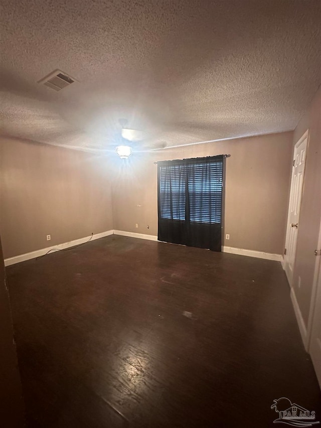 unfurnished room with baseboards, visible vents, and a textured ceiling