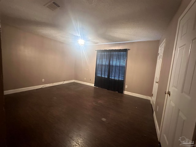 unfurnished room with baseboards, visible vents, and a textured ceiling