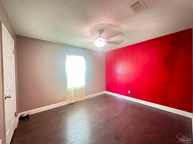 spare room featuring visible vents, dark wood finished floors, baseboards, and ceiling fan