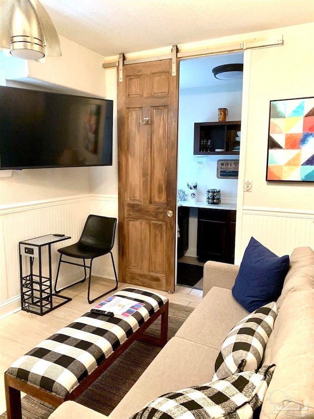 living room with a barn door and light wood-type flooring