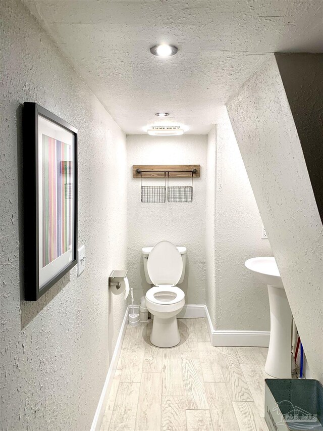 bathroom featuring a textured ceiling, toilet, and hardwood / wood-style flooring