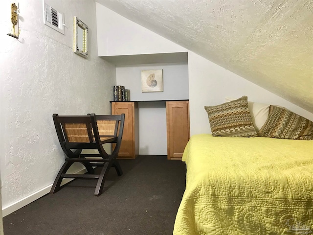 carpeted bedroom with a textured ceiling and vaulted ceiling