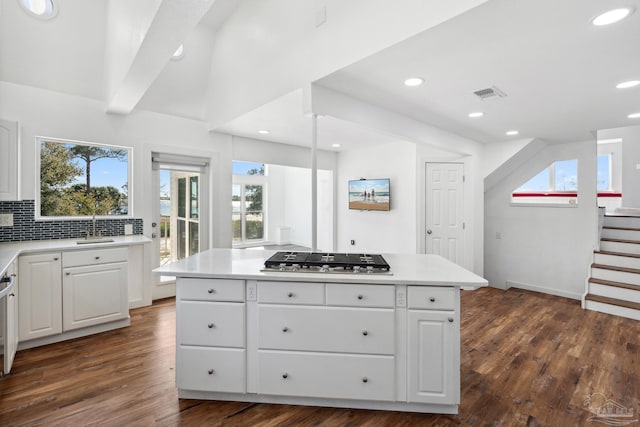 kitchen with dark hardwood / wood-style flooring, a kitchen island, white cabinets, and stainless steel gas cooktop