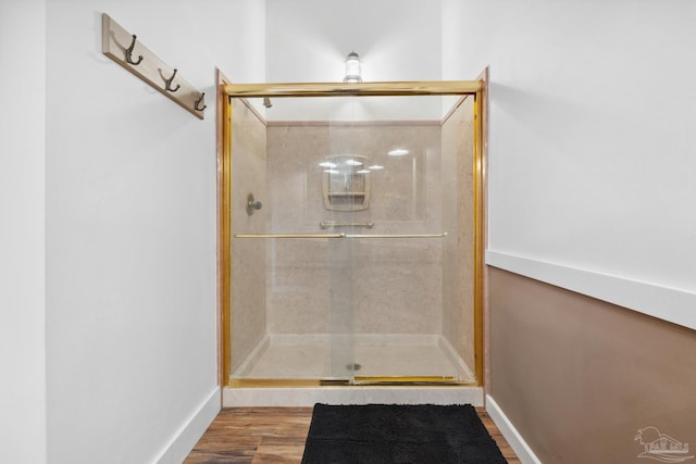 bathroom with a shower with shower door and hardwood / wood-style flooring