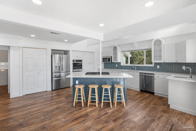 kitchen with dark wood-type flooring, sink, appliances with stainless steel finishes, a kitchen island, and white cabinetry