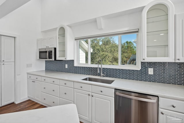 kitchen with decorative backsplash, appliances with stainless steel finishes, sink, white cabinets, and dark hardwood / wood-style floors