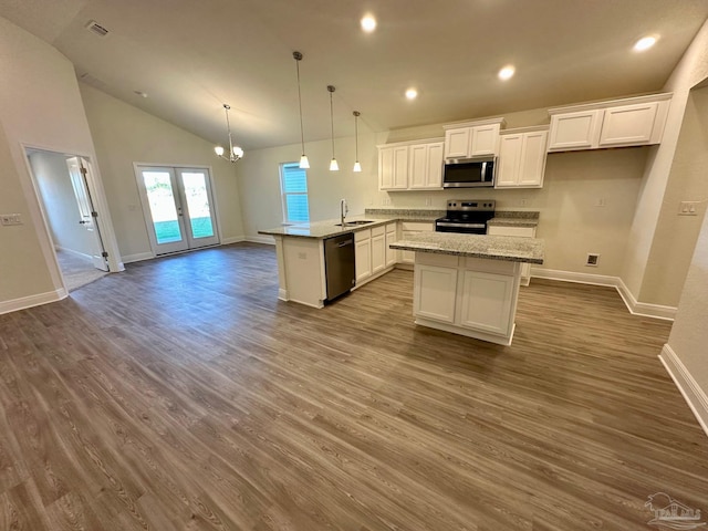 kitchen featuring kitchen peninsula, appliances with stainless steel finishes, wood-type flooring, white cabinetry, and hanging light fixtures