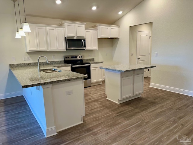 kitchen with kitchen peninsula, sink, white cabinets, and appliances with stainless steel finishes