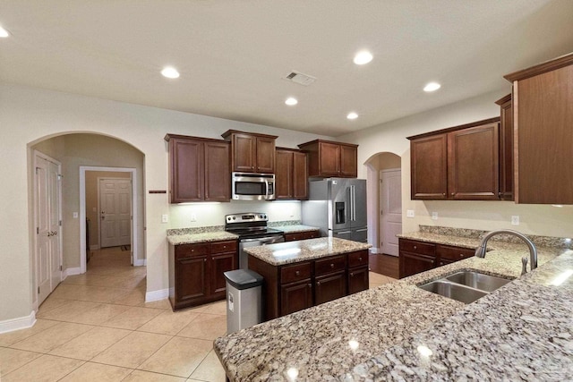 kitchen featuring a center island, sink, light stone countertops, and stainless steel appliances