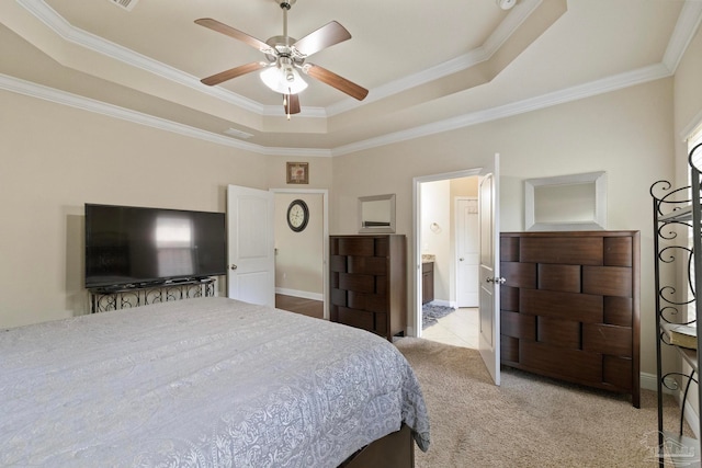 carpeted bedroom featuring a raised ceiling, connected bathroom, crown molding, and ceiling fan