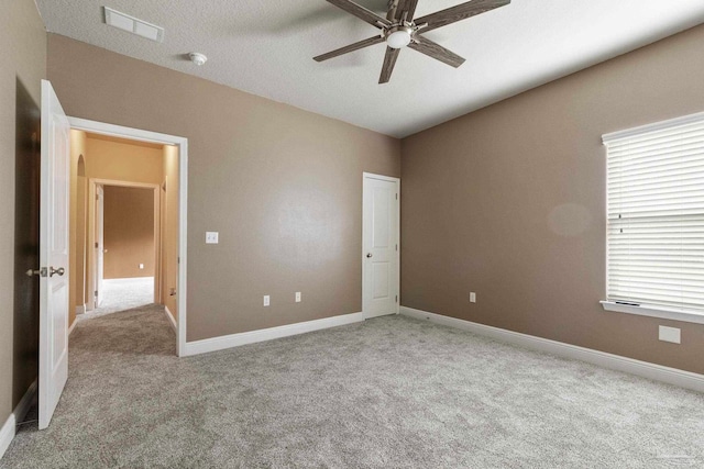 unfurnished bedroom featuring ceiling fan, light colored carpet, and a textured ceiling