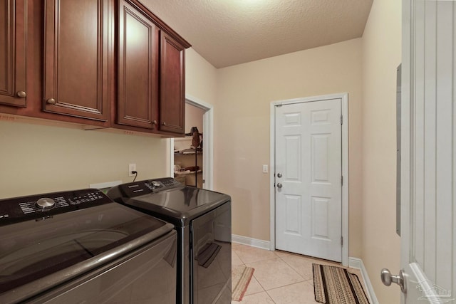 clothes washing area featuring washer and clothes dryer, light tile patterned floors, cabinets, and a textured ceiling