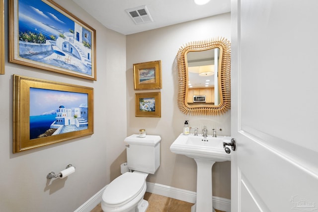half bathroom featuring visible vents, baseboards, and toilet