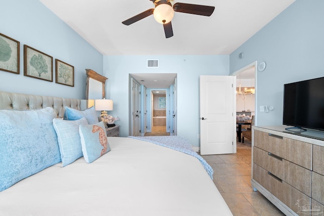 bedroom featuring ensuite bath, light tile patterned floors, visible vents, and ceiling fan