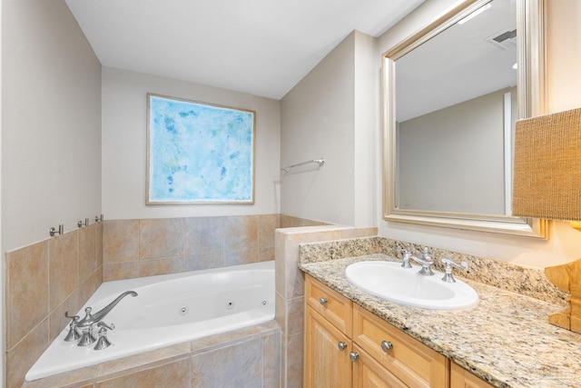 bathroom with visible vents, a tub with jets, and vanity