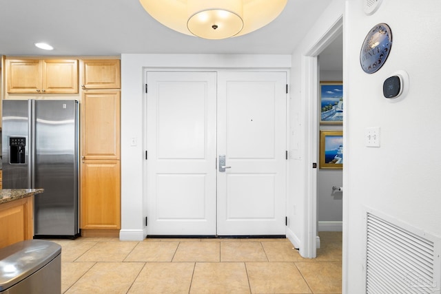kitchen with visible vents, light brown cabinets, stainless steel fridge, light tile patterned floors, and baseboards