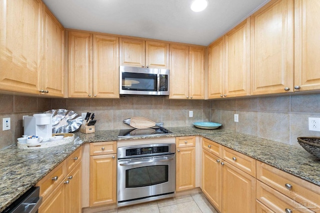 kitchen with light tile patterned floors, dark stone counters, light brown cabinetry, appliances with stainless steel finishes, and tasteful backsplash