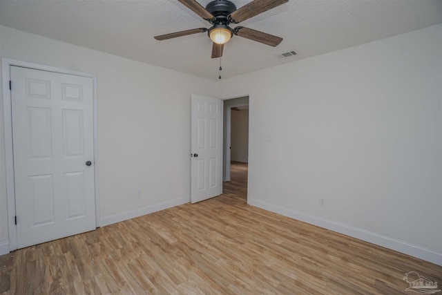 empty room featuring ceiling fan, light wood-type flooring, and a textured ceiling