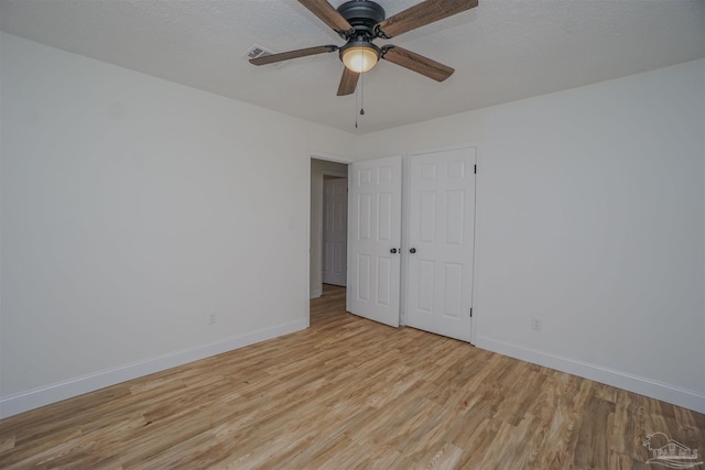 spare room featuring a textured ceiling, light hardwood / wood-style floors, and ceiling fan