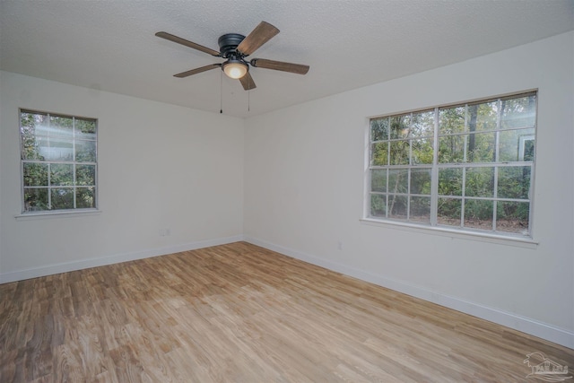 spare room with a textured ceiling, light wood-type flooring, plenty of natural light, and ceiling fan